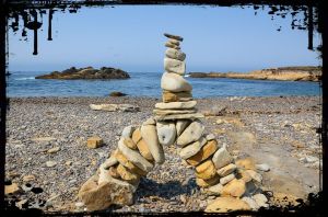rocks piled in a balanced arrangement on a beach with the sea behind them
